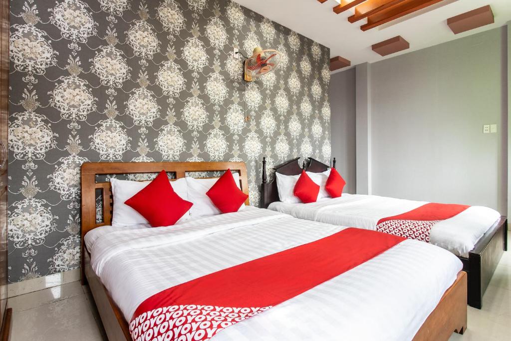 2 bedden in een slaapkamer met rode en witte kussens bij Honey Hotel Da Nang in Da Nang