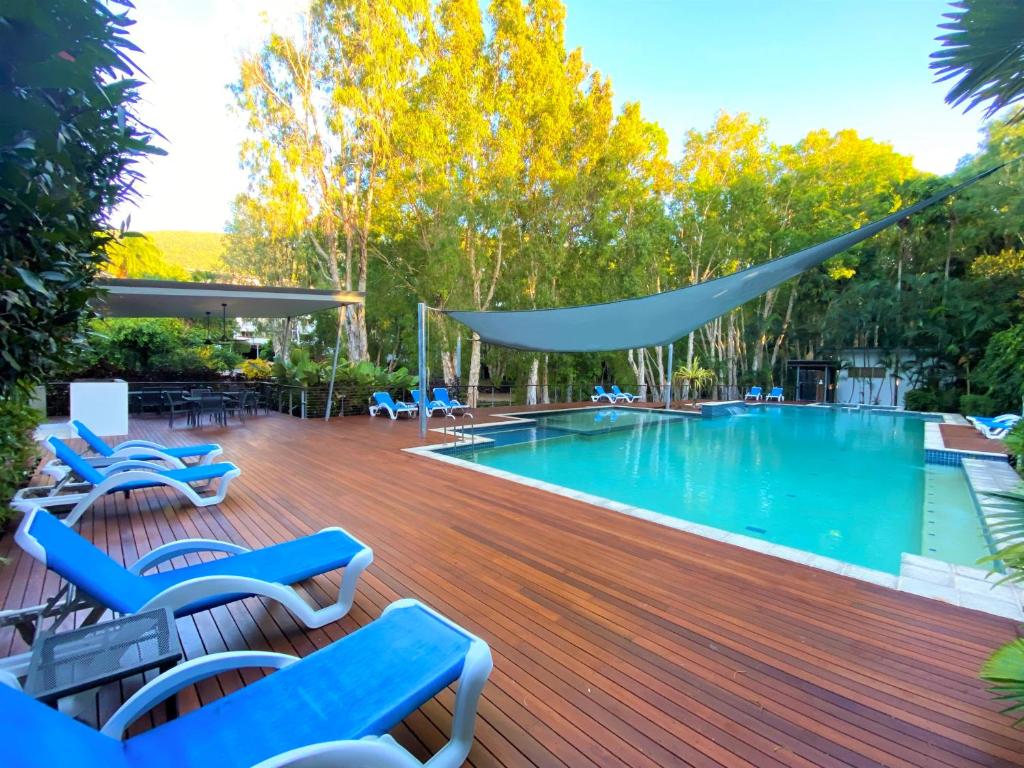 a deck with chairs and a swimming pool at Sanctuary Palm Cove in Palm Cove