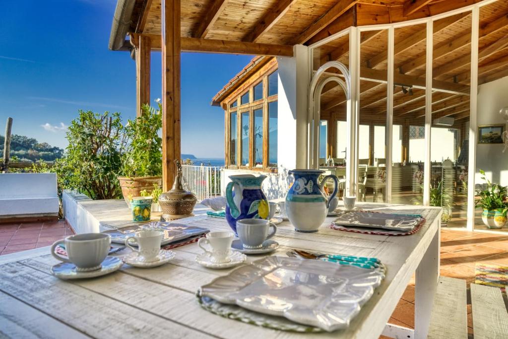 een houten tafel met borden en kopjes op een patio bij Villa Lorelei in Massa Lubrense