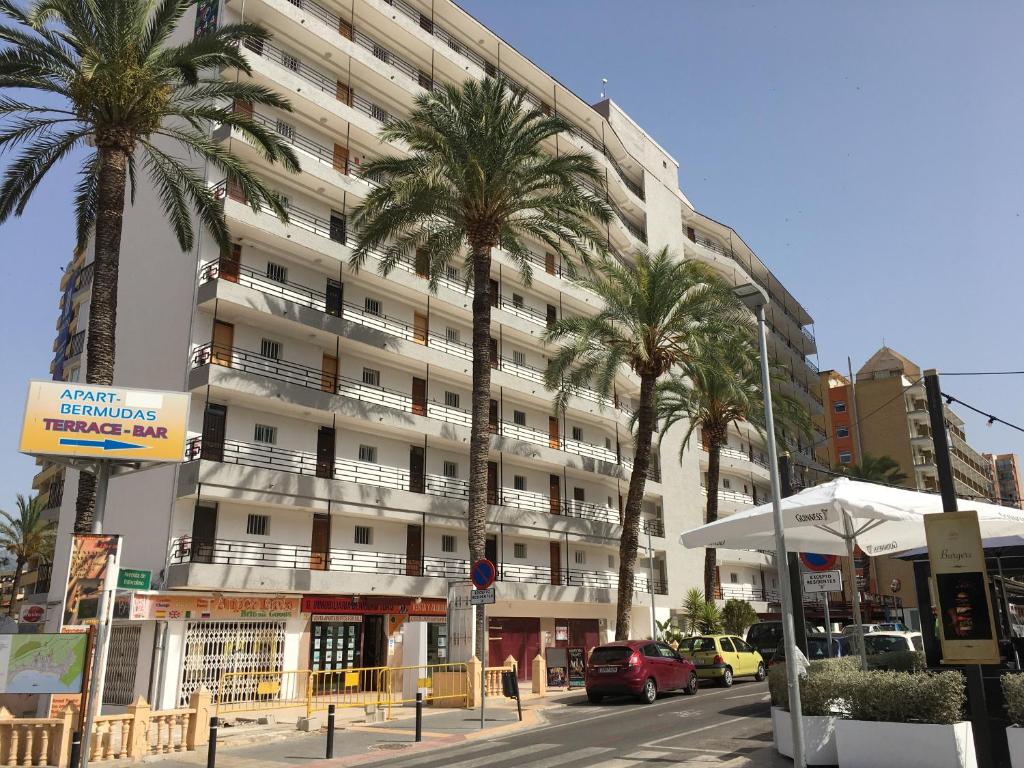 un grand bâtiment avec des palmiers devant dans l'établissement BERMUDAS-TURIS Apartamentos, à Benidorm