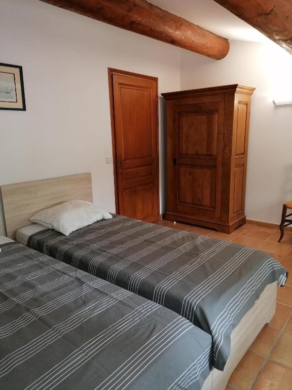 a bedroom with two beds and a wooden cabinet at mas cantarello in Rognes