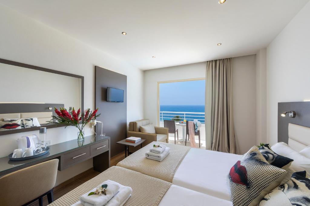 a hotel room with a bed and a desk with a view at Queens Bay Hotel in Paphos