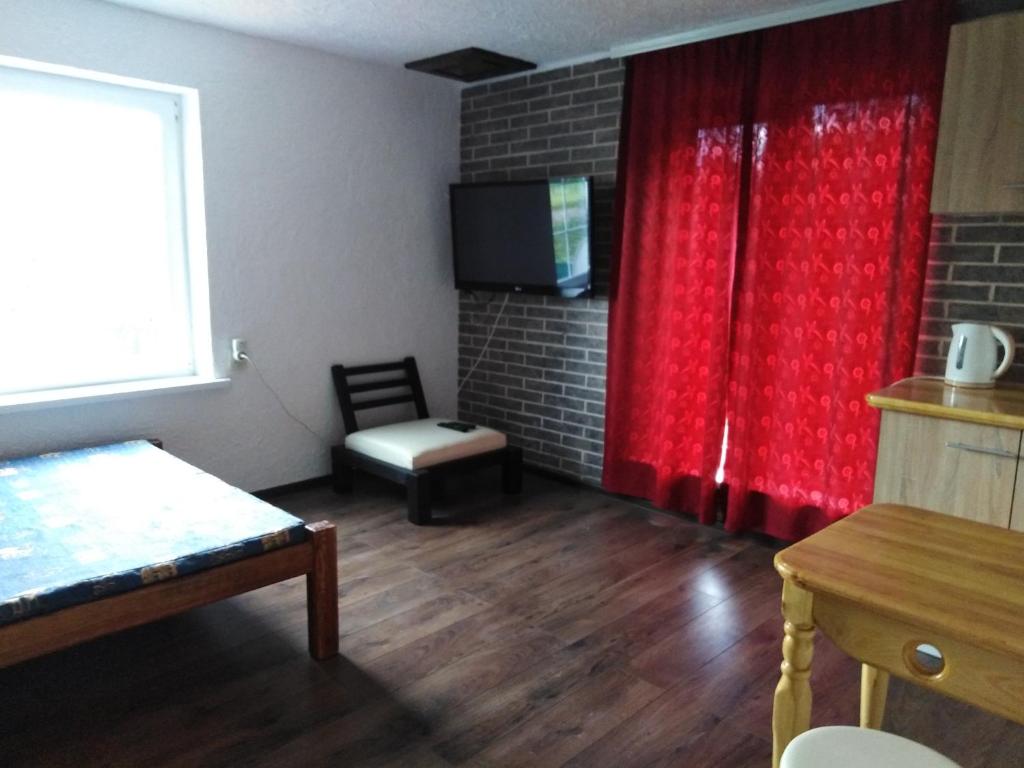 une chambre avec un rideau rouge et une chaise dans l'établissement Гостевая комната, à Kiev