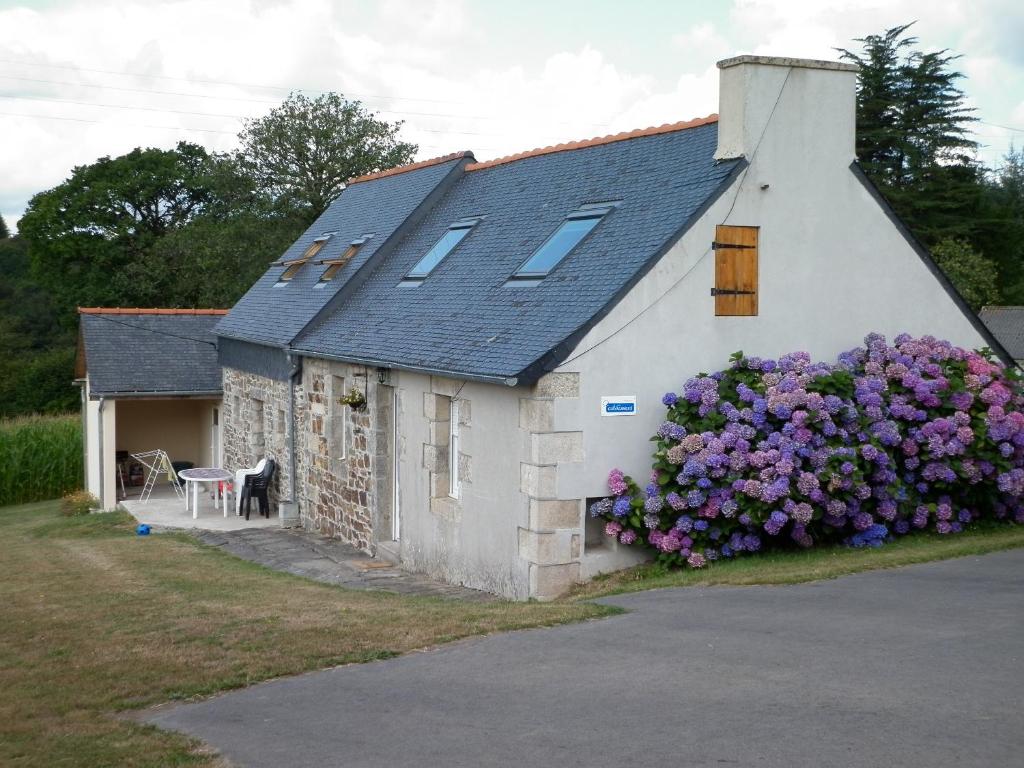 een klein wit gebouw met een bos bloemen erop bij Gîte Clévacances dans le Finistère in Scrignac