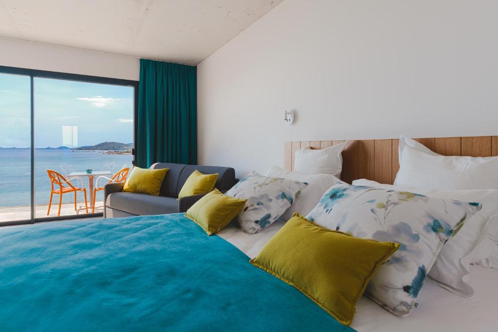 a bedroom with a bed with a view of the ocean at Hotel le Jardin d'Emile in Porticcio