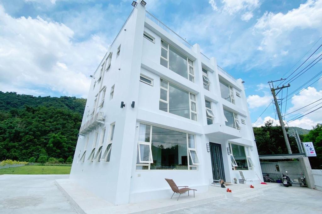 ein weißes Gebäude mit einem Stuhl davor in der Unterkunft 埔里-阮兜小丘 in Puli