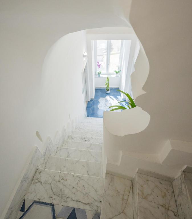 a staircase with white walls and marble stairs with a plant at Le Volte Procida Home in Procida