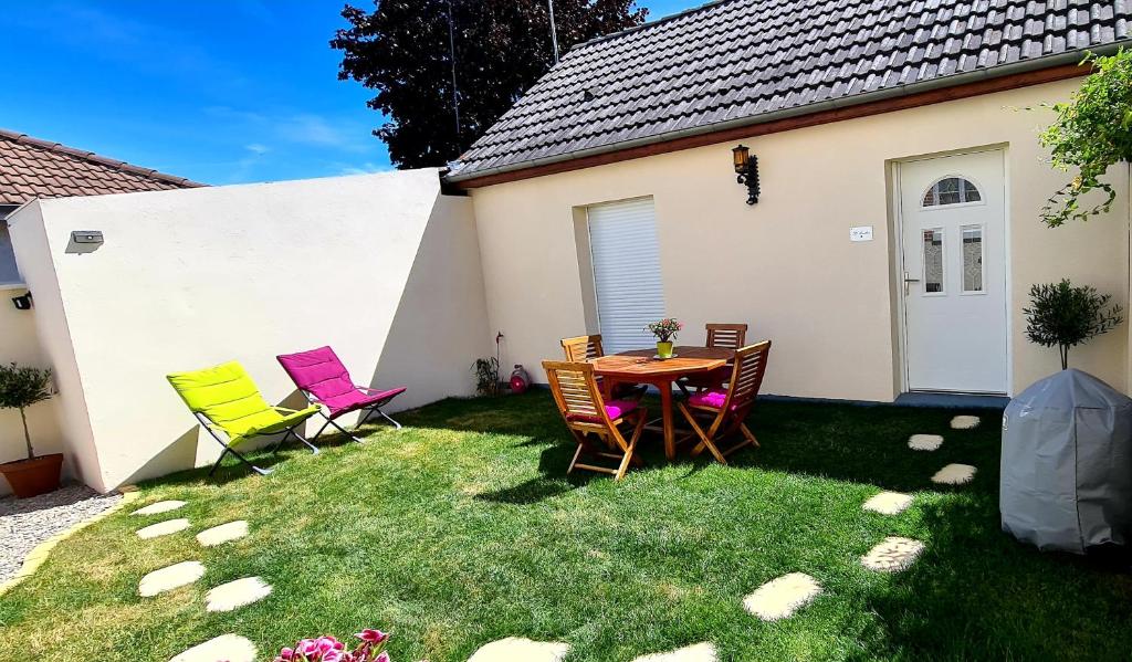 eine Terrasse mit Stühlen und einem Tisch im Gras in der Unterkunft "LE PAVILLON" Maisonnette 150 m gare des Aubrais in Fleury-les-Aubrais