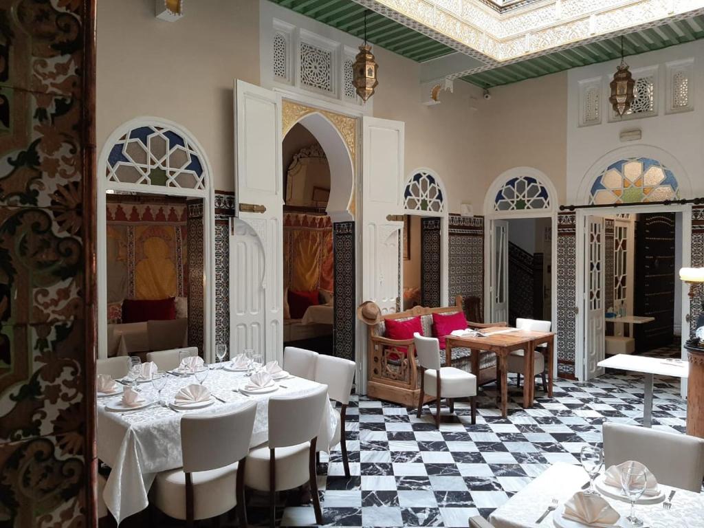 un restaurant avec des tables et des chaises blanches et un sol en damier dans l'établissement El Reducto, à Tetouan