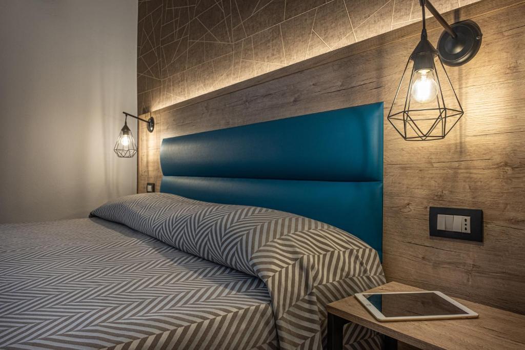 a bedroom with a bed with a blue headboard and a table at Cuneo Hotel in Cuneo