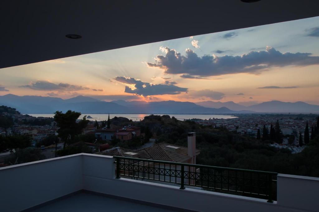 een uitzicht op de zonsondergang vanaf het balkon van een huis bij Fedra - Panoramic Sea View in Nafplio