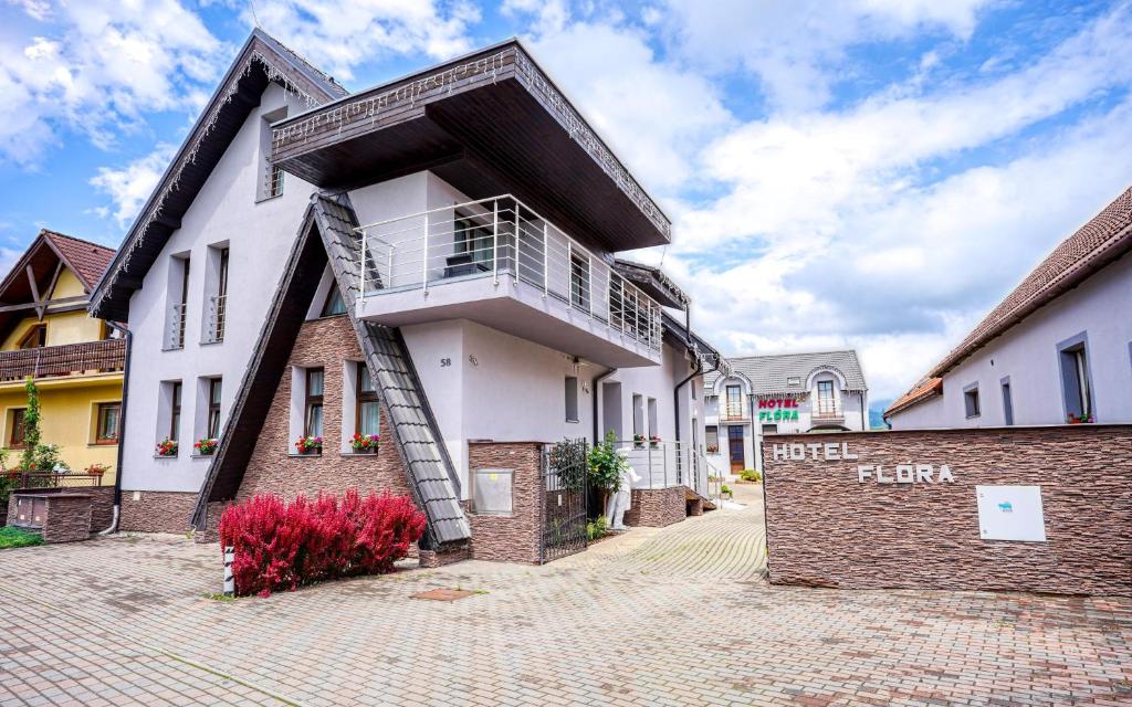 a white building with a balcony on top of it at Hotel Flora in Bešeňová