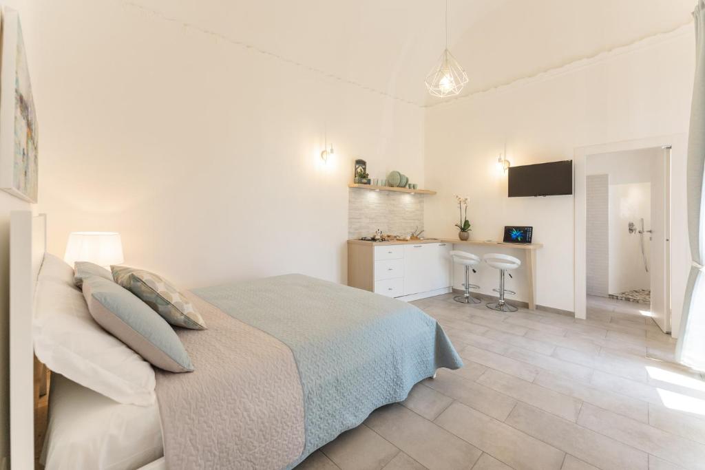 a white bedroom with a bed and a kitchen at Le Volte Procida Home in Procida