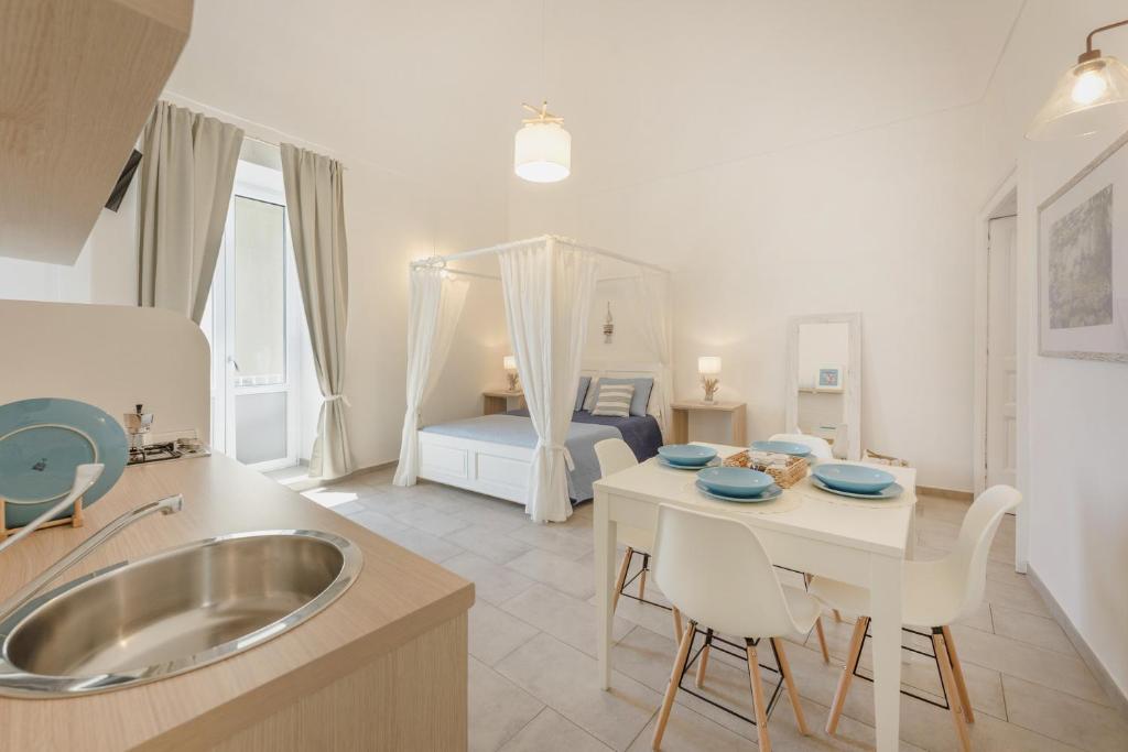 a kitchen with a sink and a table and a bed at Le Volte Procida Home in Procida