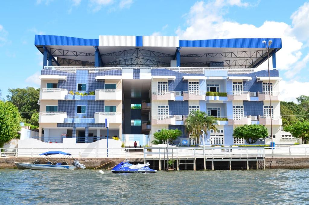 a building on the water with a boat in front at Hotel Mirante Da Ilha in Alter do Chao