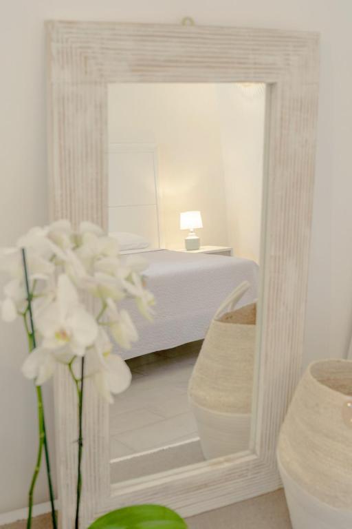 a white bedroom with a bed and a mirror at Le Volte Procida Home in Procida
