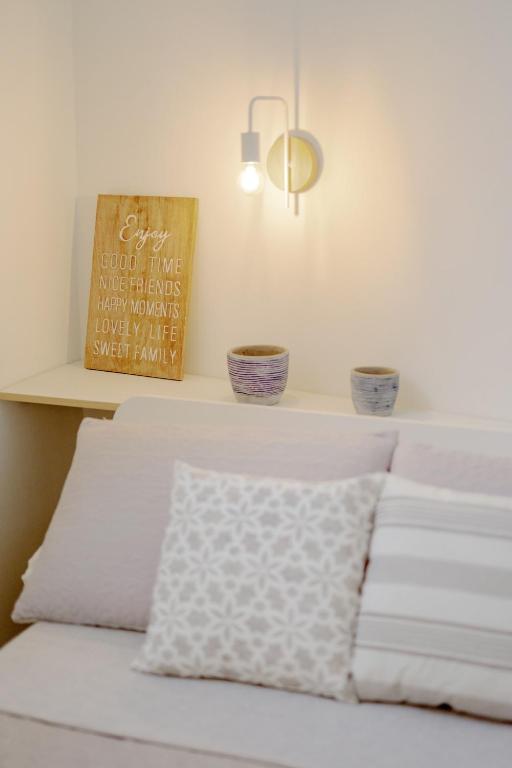 a bed with white pillows and a shelf with plants at Le Volte Procida Home in Procida