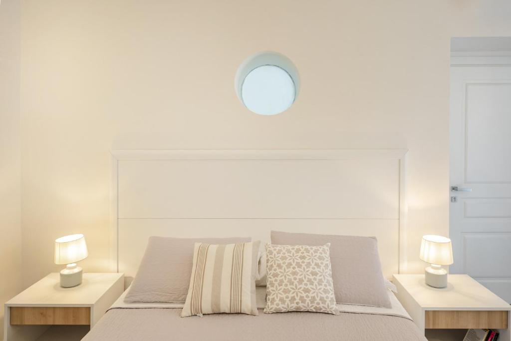 a white bedroom with a bed with two lamps at Le Volte Procida Home in Procida