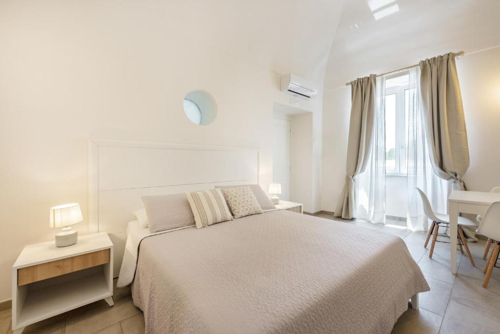 a white bedroom with a large bed and a desk at Le Volte Procida Home in Procida