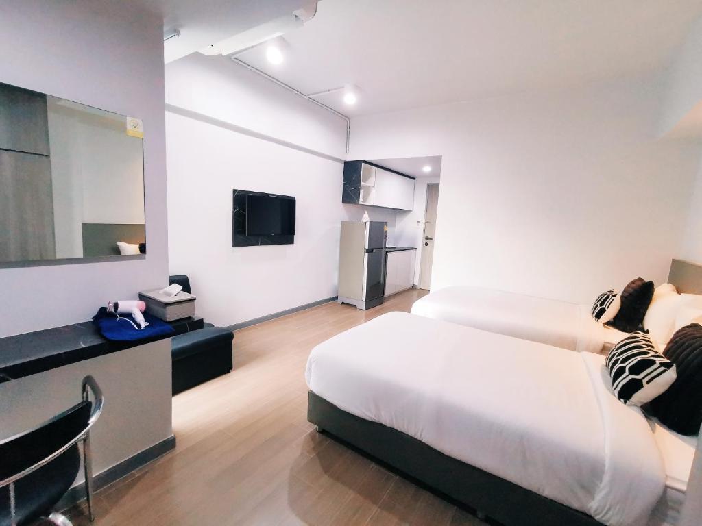 A twin room with a kitchenette, TV, desk and two beds in an open layout.