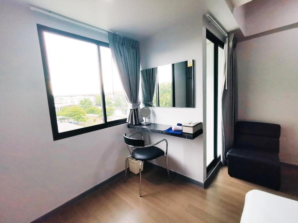 A compact desk beside a large window, with a mirror and occasional chair.