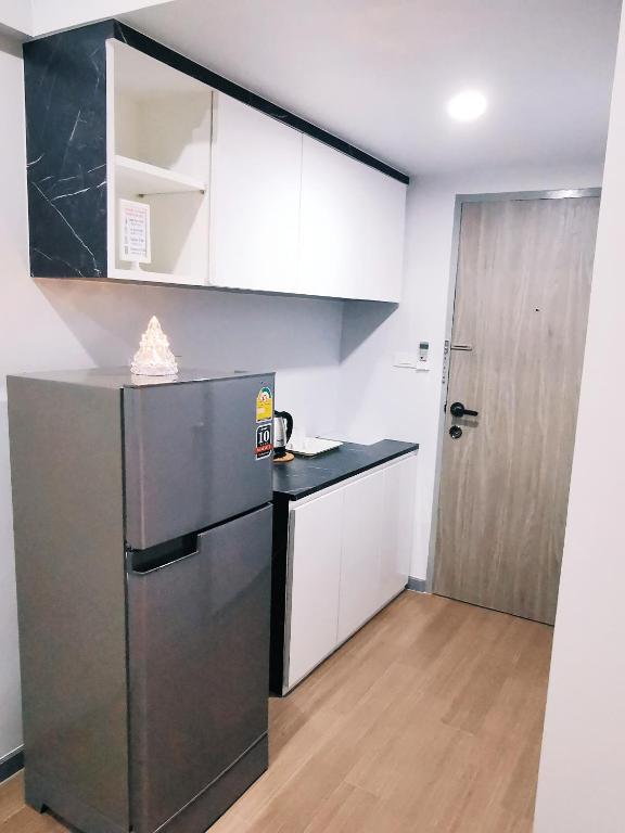 A compact in-room kitchenette with a tall refrigerator, counter and overhead cabinets.