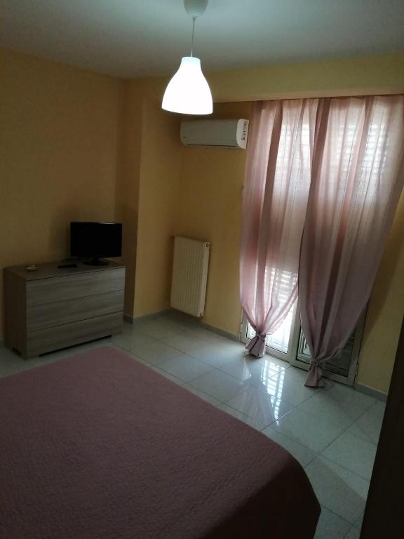 a bedroom with pink curtains and a bed and a tv at Stanza Olmo Caserta in Caserta