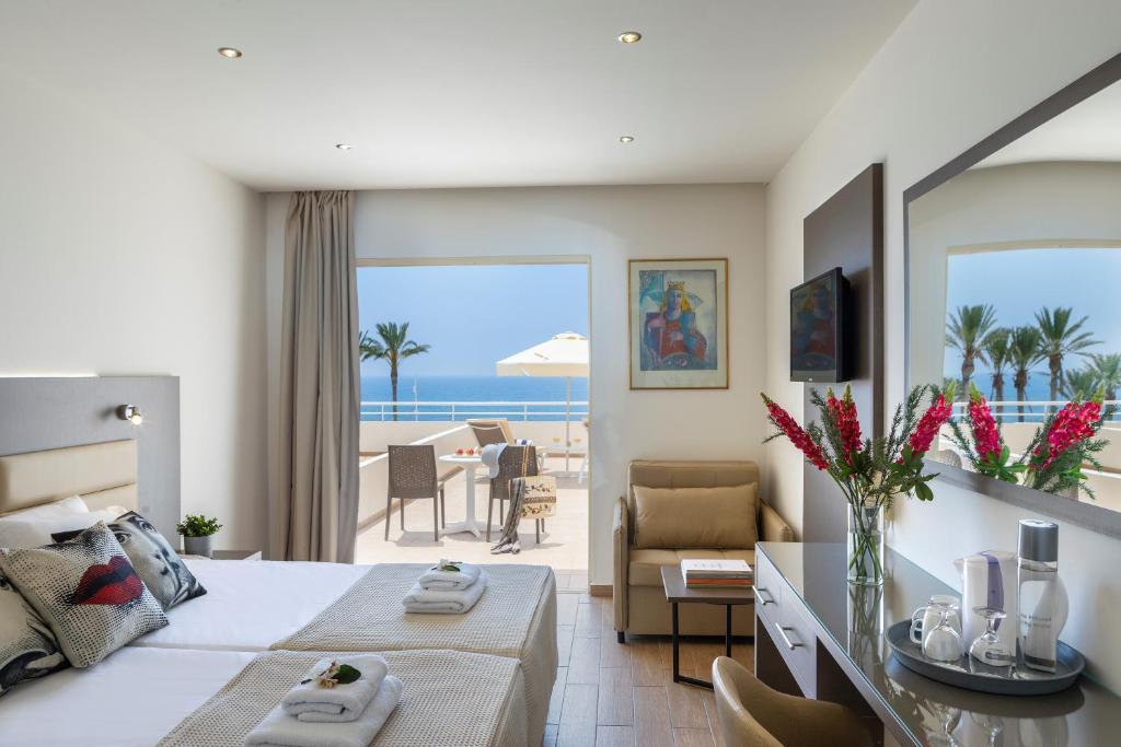 a hotel room with a bed and a view of the ocean at Queens Bay Hotel in Paphos