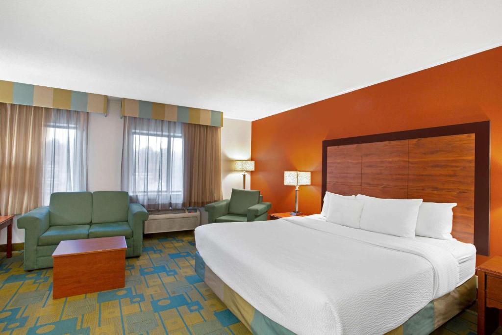 una habitación de hotel con una cama grande y sillas en La Quinta Inn by Wyndham Auburn Worcester, en Auburn