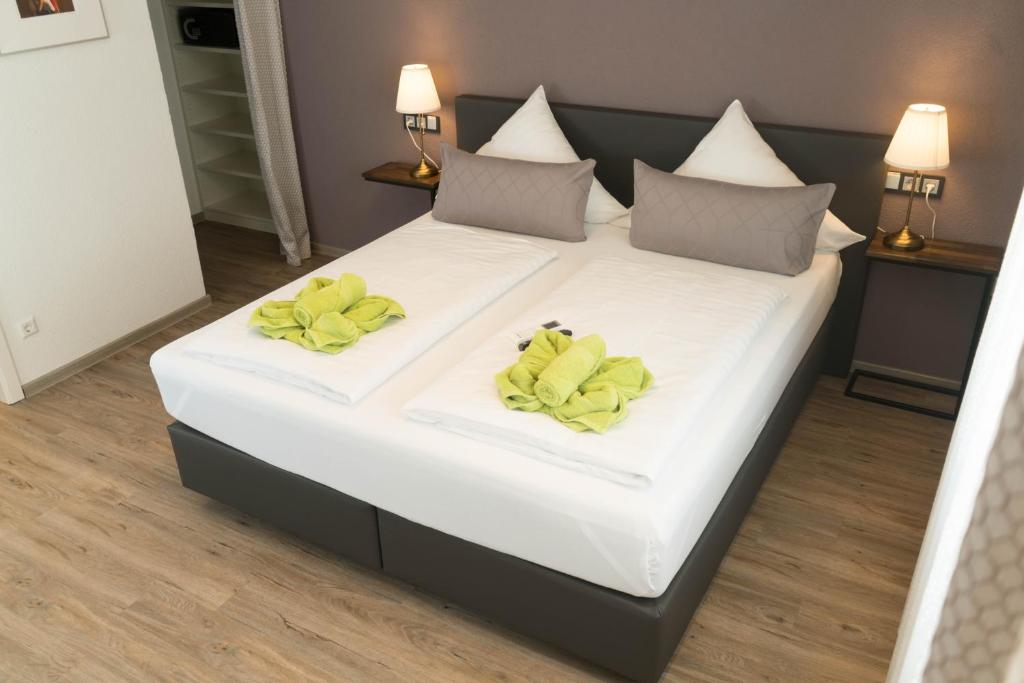 Una cama blanca grande con toallas amarillas. en CityApartment K1 KLIMATISIERT en Friedrichshafen