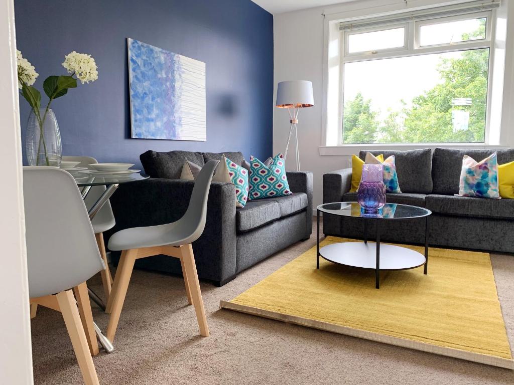 a living room with a couch and a table at Modern And Vibrantly Designed Apartment in Motherwell