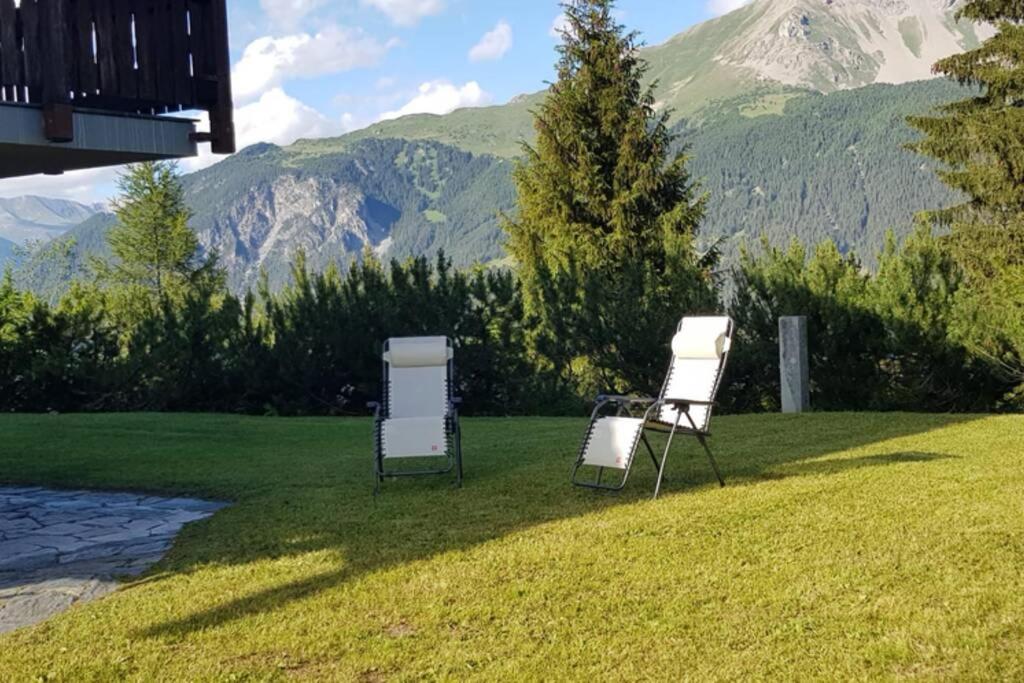 two chairs sitting in the grass with mountains in the background at Chalet Wulli in der Nähe der Skianlagen Savognin in Savognin