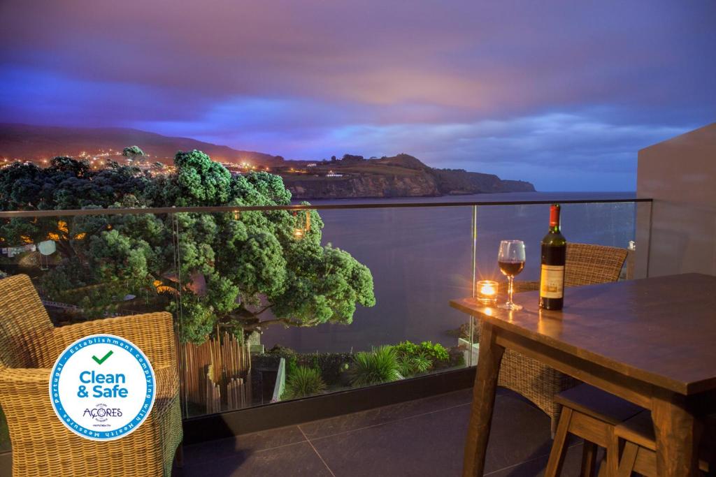 een fles wijn op een tafel op een balkon bij Graviana - Pedra Negra Charming House in Lagoa