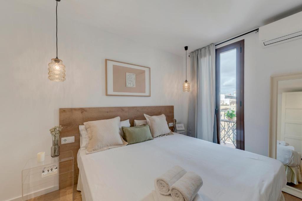 1 dormitorio con 1 cama blanca grande y balcón en Happy Apartments en Barcelona