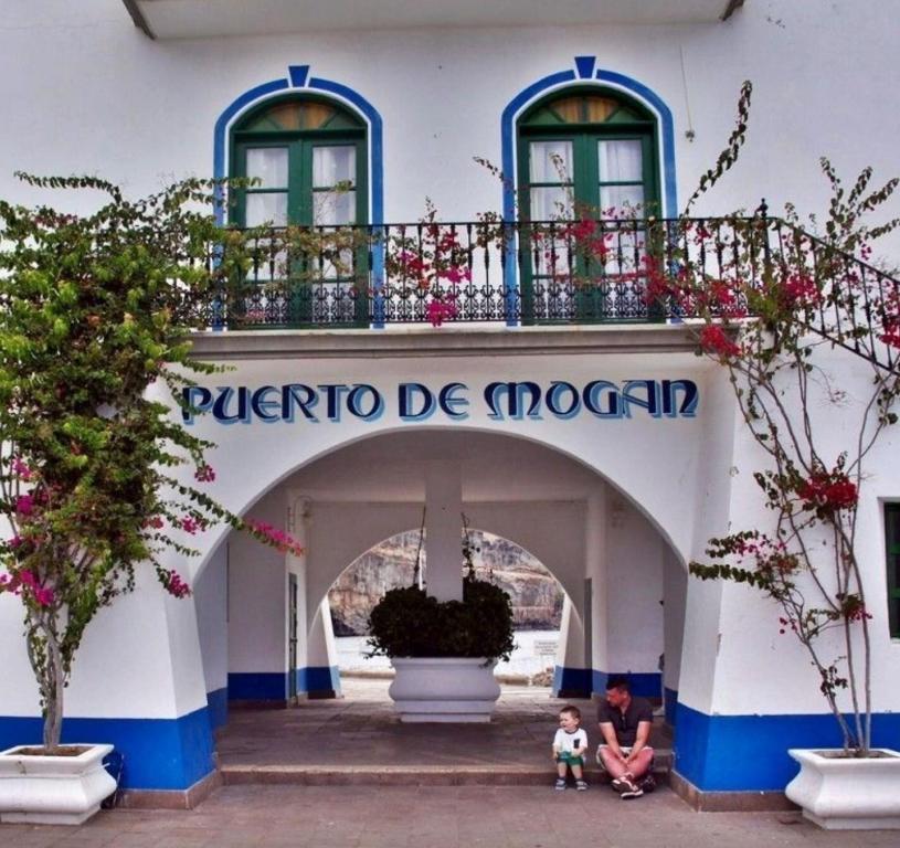 a woman and child sitting in front of a building at HarbourPlaya de Mogan in Puerto de Mogán