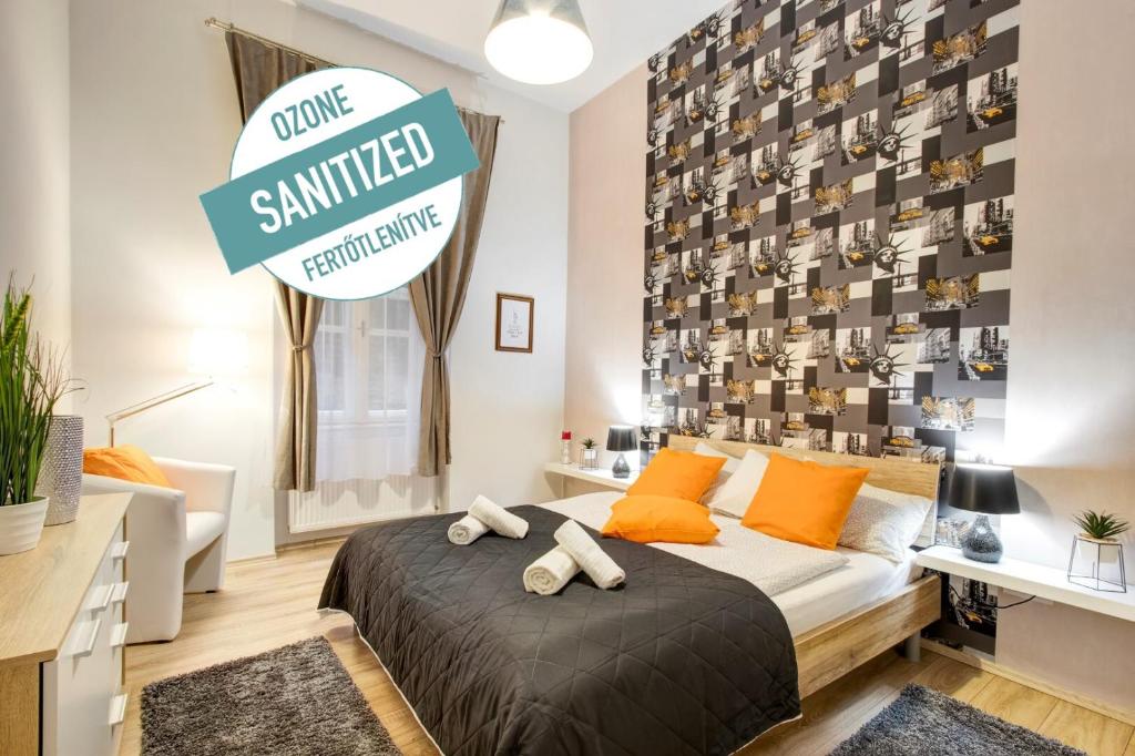 ブダペストにあるStandard Apartment by Hi5 - Weiner Leoのベッドルーム1室(オレンジ色の枕と読書用のサイン付)
