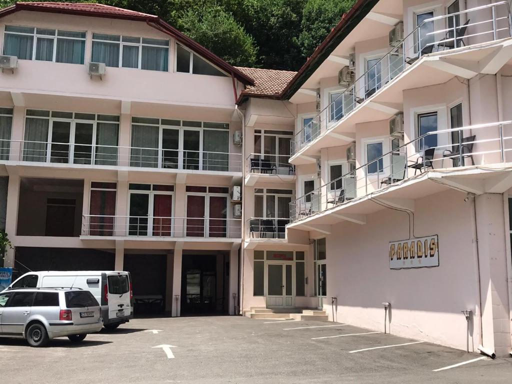 a building with a car parked in a parking lot at Pensiunea Paradis in Băile Herculane