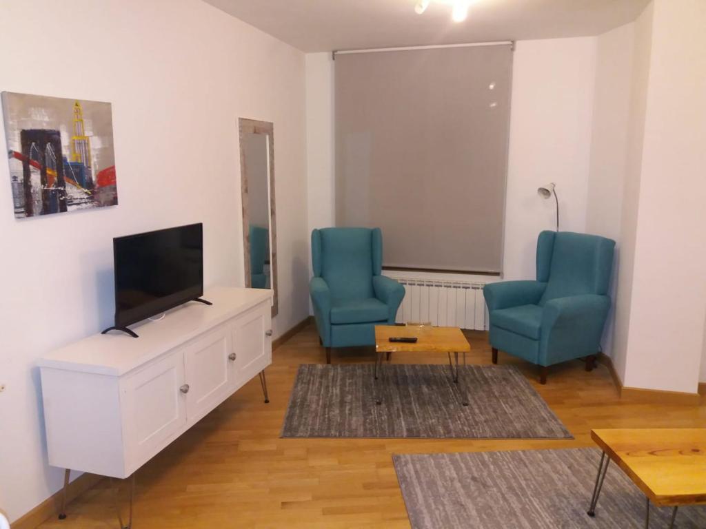 een woonkamer met twee blauwe stoelen en een flatscreen-tv bij Saron Centro 1 in Sarón
