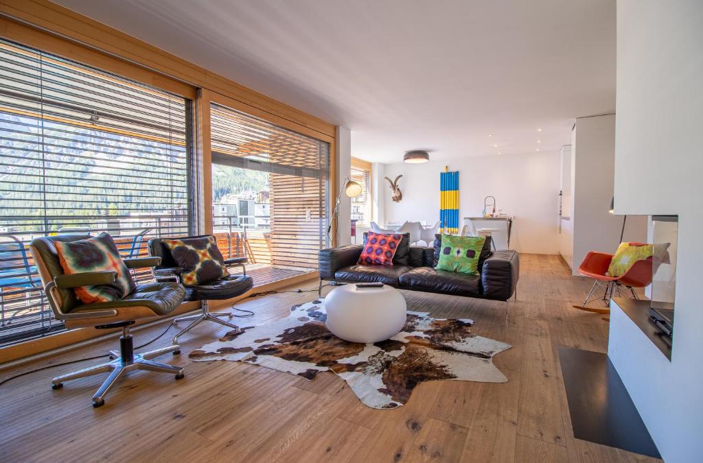 ein Wohnzimmer mit einem Sofa und Stühlen sowie einem großen Fenster in der Unterkunft Salis 06 by Arosa Holiday in Arosa