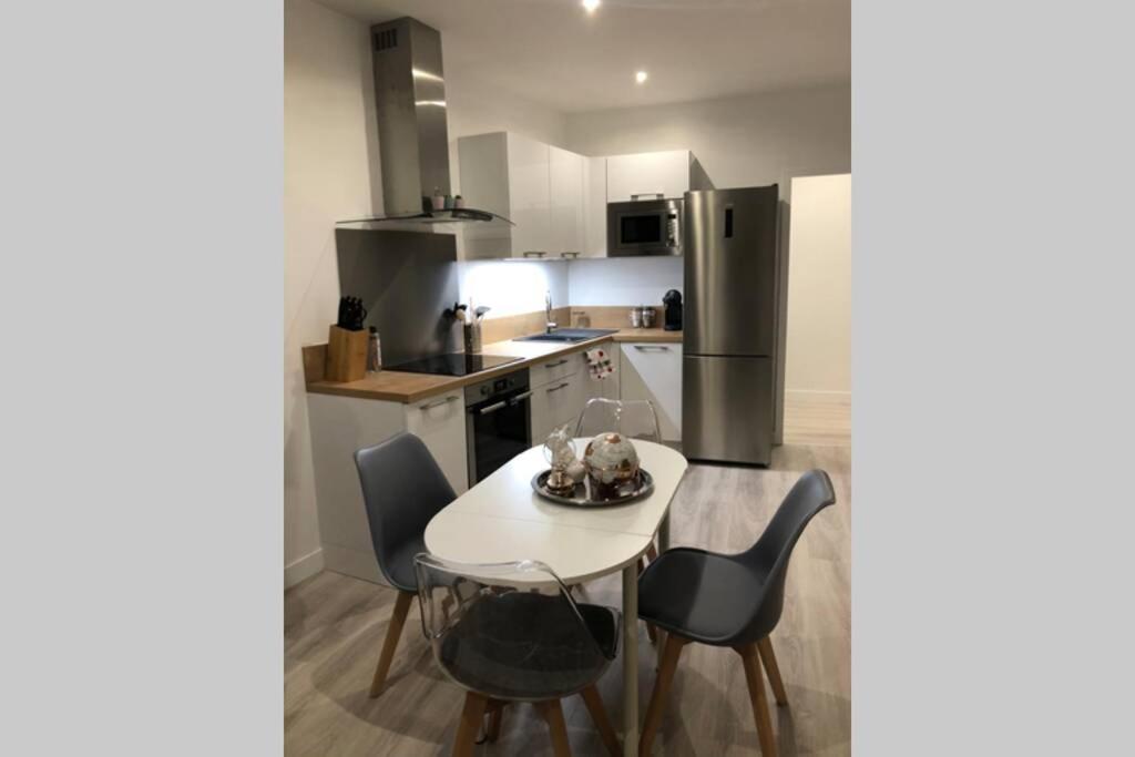 une cuisine avec une table, des chaises et un réfrigérateur dans l'établissement Le Cocon Château de chantilly Roissy Parc asterix JO 2024, à Coye-la-Forêt