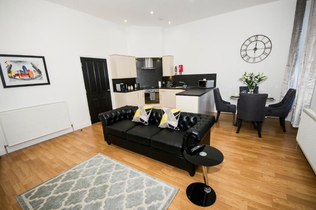 sala de estar con sofá negro y cocina en Parkhill Luxury Serviced Apartments - City Centre Apartments en Aberdeen