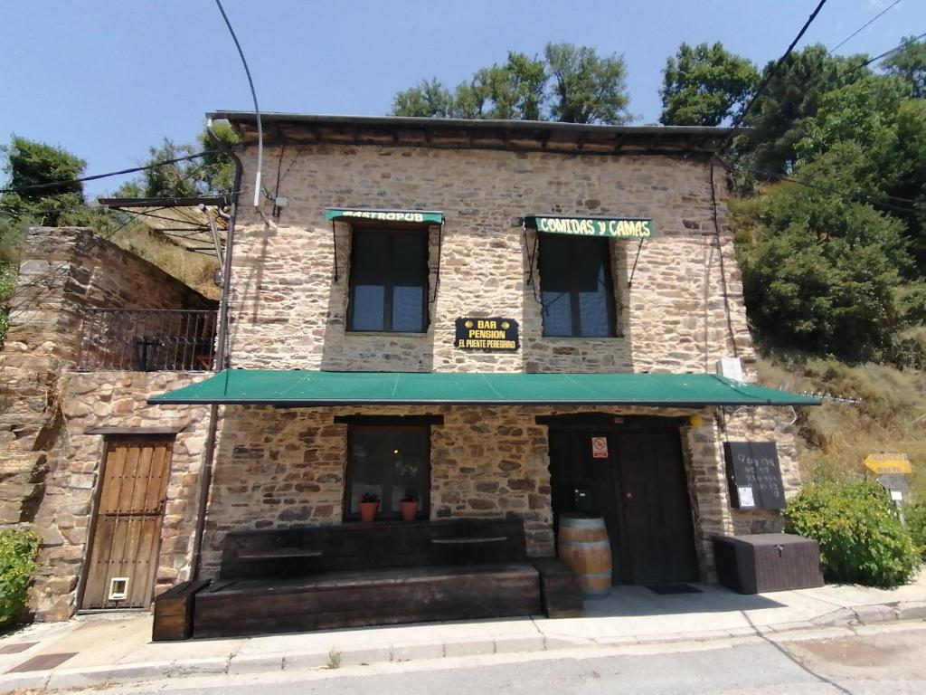 un antiguo edificio de ladrillo con toldo verde en El Puente Peregrino, en Trabadelo