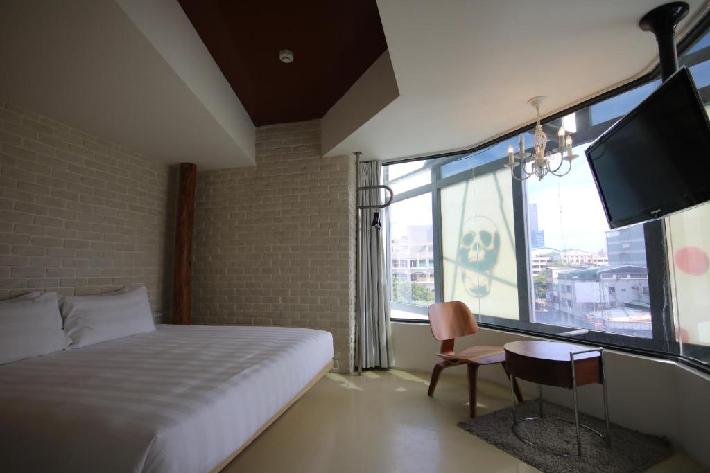 a bedroom with a bed and a tv and a chair at Hotel Papa Whale-Kaohsiung Formosa Boulevard in Kaohsiung