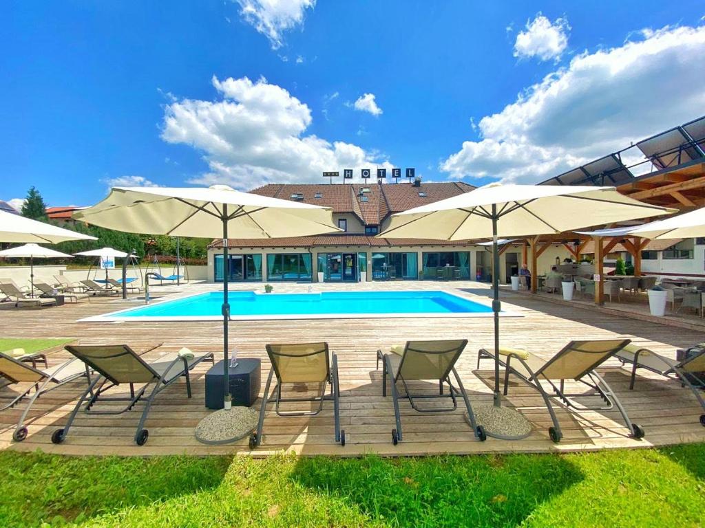um grupo de cadeiras e guarda-sóis ao lado de uma piscina em 16 Lakes Hotel em Grabovac
