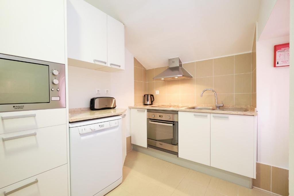 a kitchen with white cabinets and a flat screen tv at Sintra Bliss A Part in Sintra
