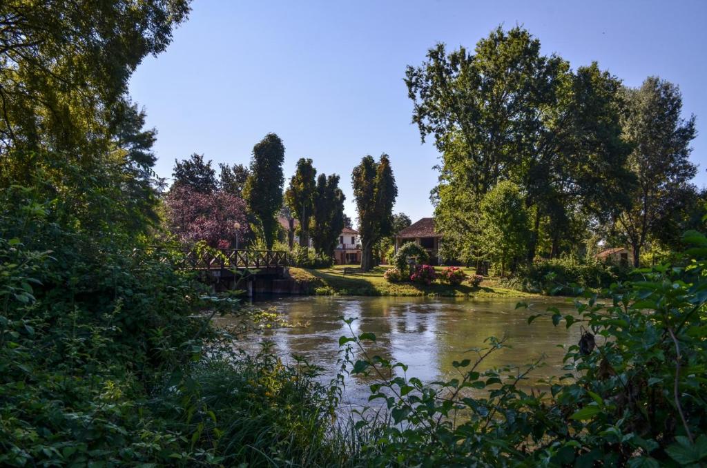 um rio num parque com árvores e uma ponte em Corte Isolo em Goito