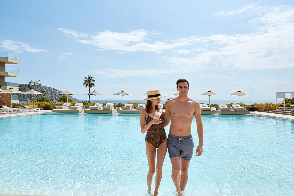 Un uomo e una donna in piedi in acqua in un resort di Vincci EverEden ad Anávissos