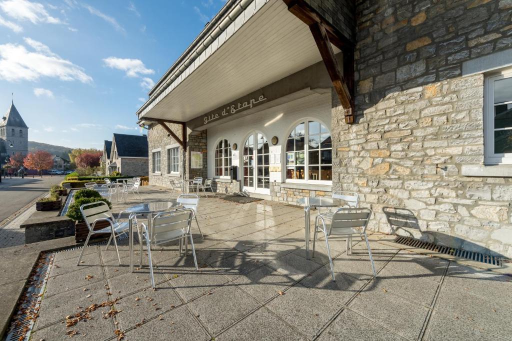 un patio avec des chaises et des tables en face d'un bâtiment dans l'établissement Gîte Kaleo Han-Sur-Lesse, à Han-sur-Lesse