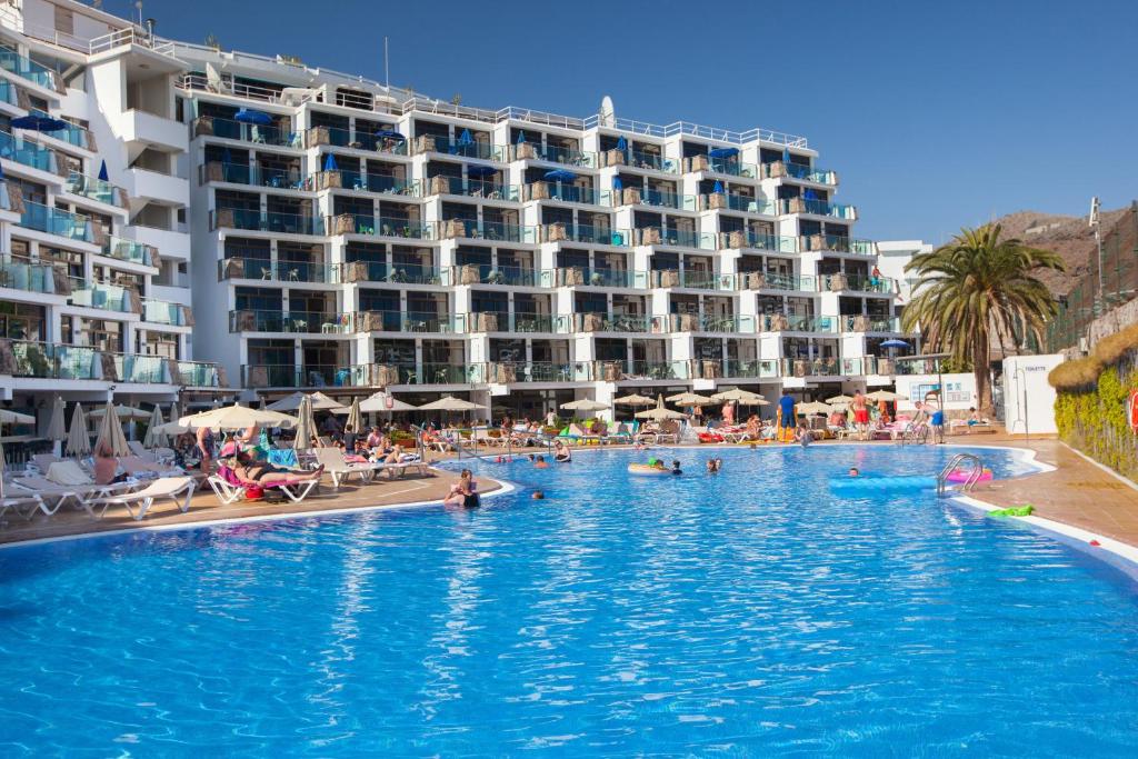 een groot zwembad met een hotel op de achtergrond bij Grupotel Revoli in Puerto Rico de Gran Canaria
