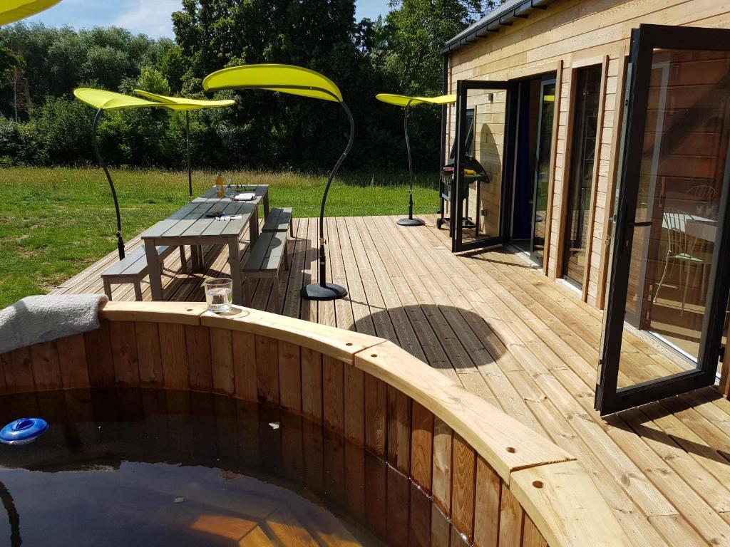 a deck with a picnic table and a yellow frisbee at Le Domaine Des Anges, écolodge in Thenay